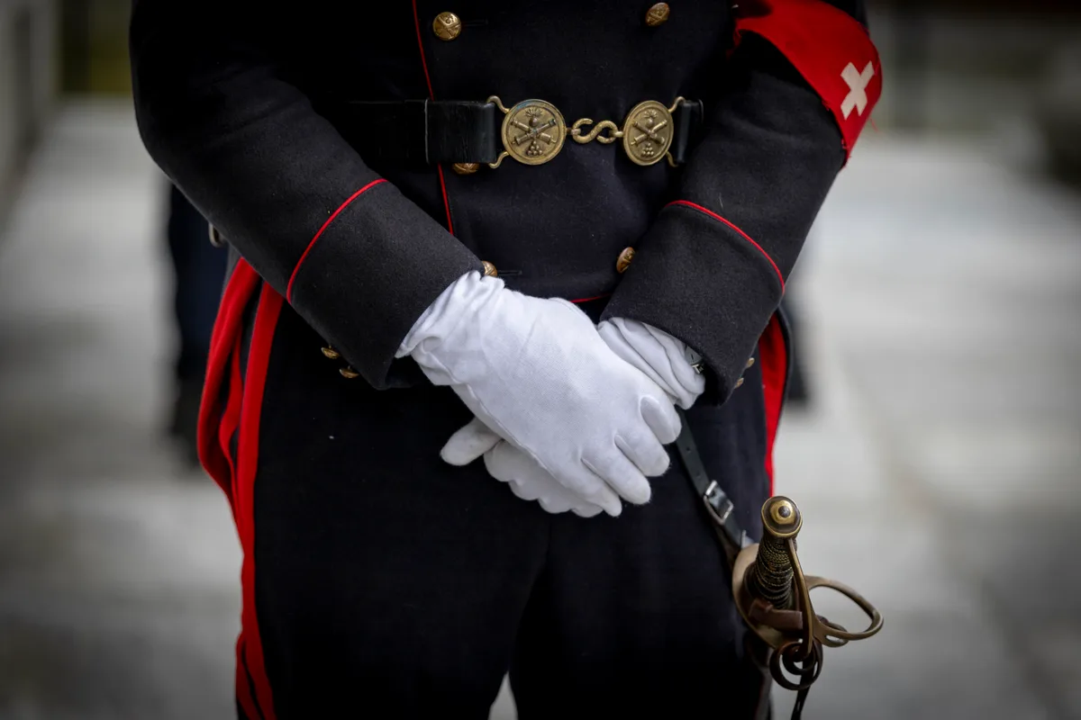 … Ehrenwache zur Begrüssung der Gäste. Man sieht die behandschuhten Hände eines uniformierten Wachmanns.